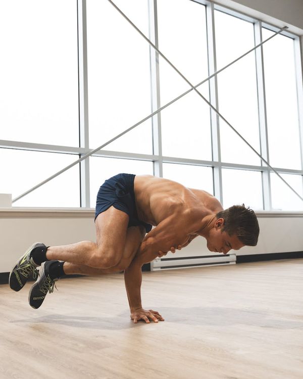 Man performing a controlled strength exercise in a modern gym.